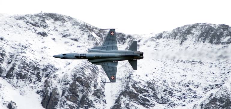 Avion de combat / chasseur survolant les Alpes et chargé de protéger l’espace aérien.